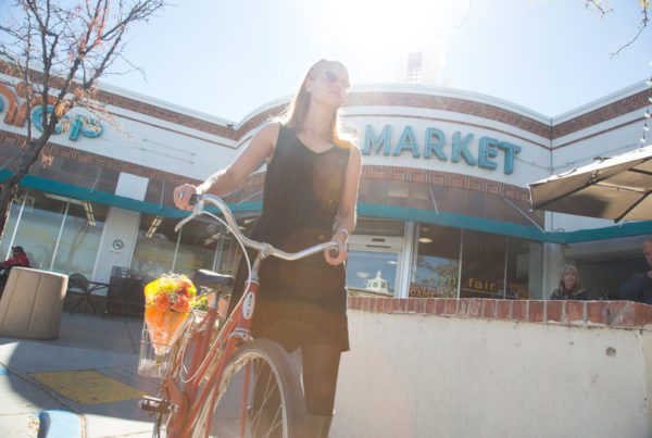 Woman walking with bicycle outside market building